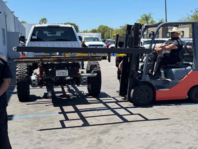 Bare F-550 chassis staged outside the shop with the forklift ready